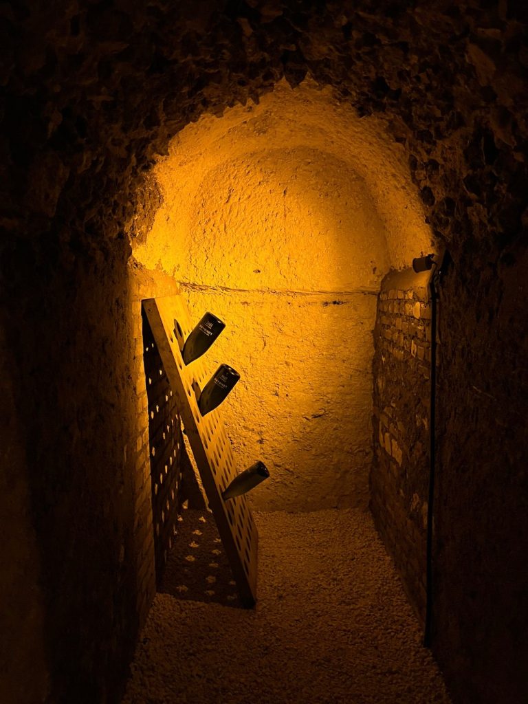 Champagne Experience Oktober 2025 Verlaten ondergrondse ruimte met verlichte muren en houten rekken.